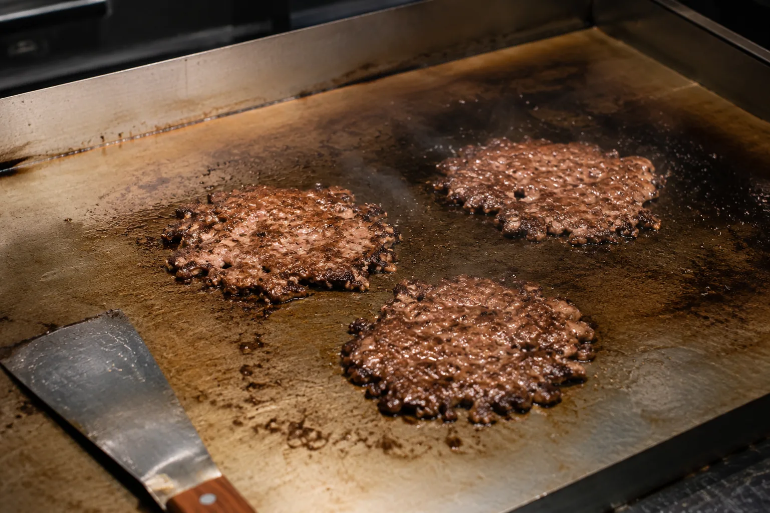 Hamburguesas cocinándose sobre una plancha de hierro